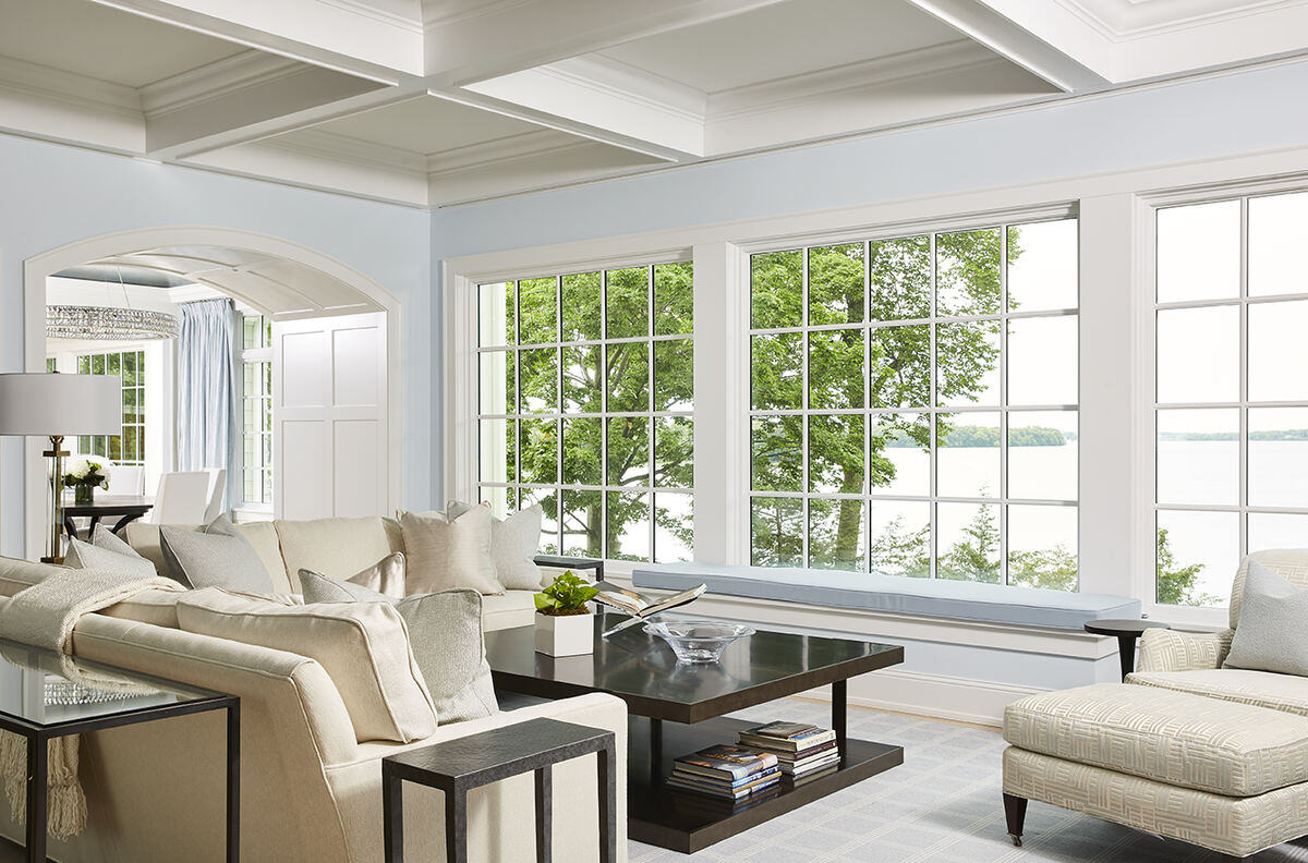 Bright living room with large windows overlooking the lake in a custom home by MA Peterson, Twin City