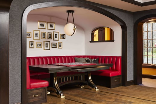 Stylish dining nook with red banquette seating and wall art in a custom home by MA Peterson, Twin City