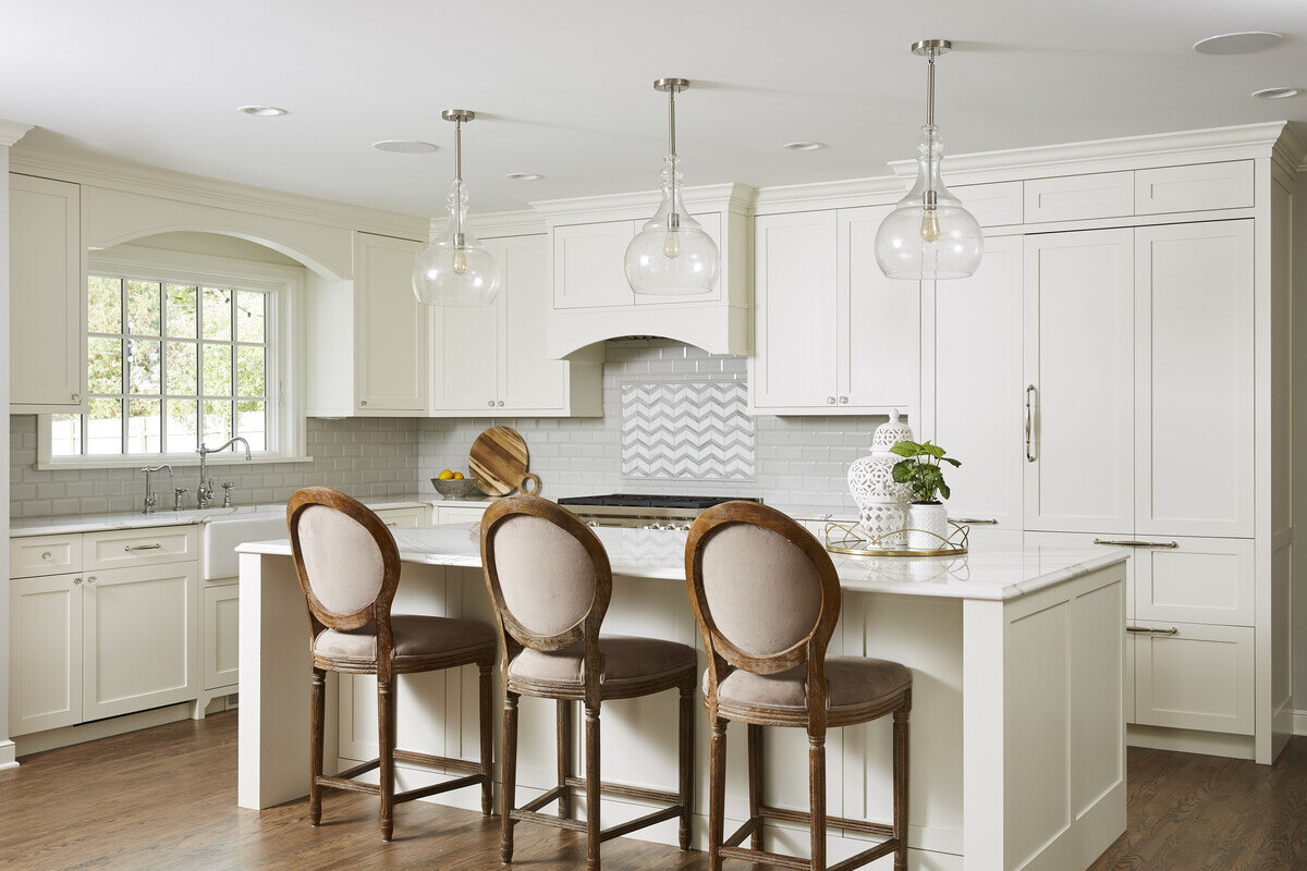 Bright white kitchen with island seating and pendant lights, designed by MA Peterson in Twin City