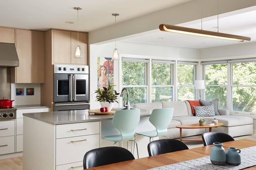 Modern kitchen and dining area with light wood cabinets, designed by MA Peterson in Twin City