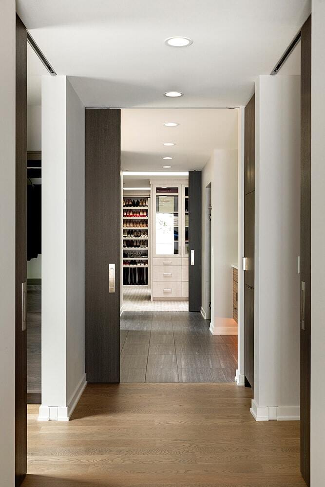 Hallway leading to a walk-in closet with organized shelves and shoe racks in a custom home by MA Peterson in the Twin Cities Hallway leading to a walk-in closet with organized shelves and shoe racks in a custom home by MA Peterson in the Twin Cities