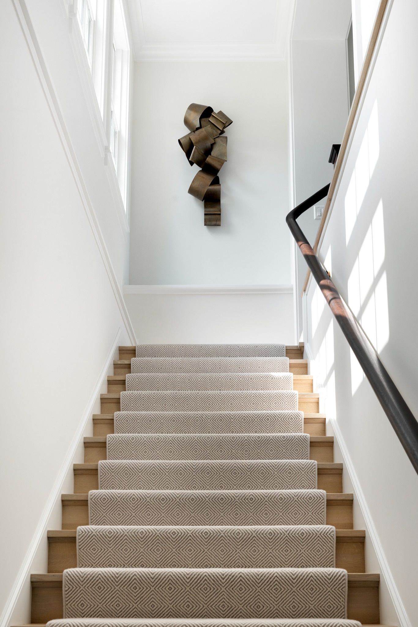 staircase with patterned runner and wall sculpture in wayzata mn custom home