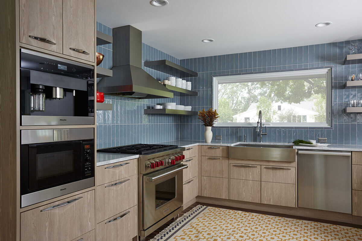 Modern kitchen with blue tile backsplash and stainless steel appliances in a Twin Cities remodel by MA Peterson