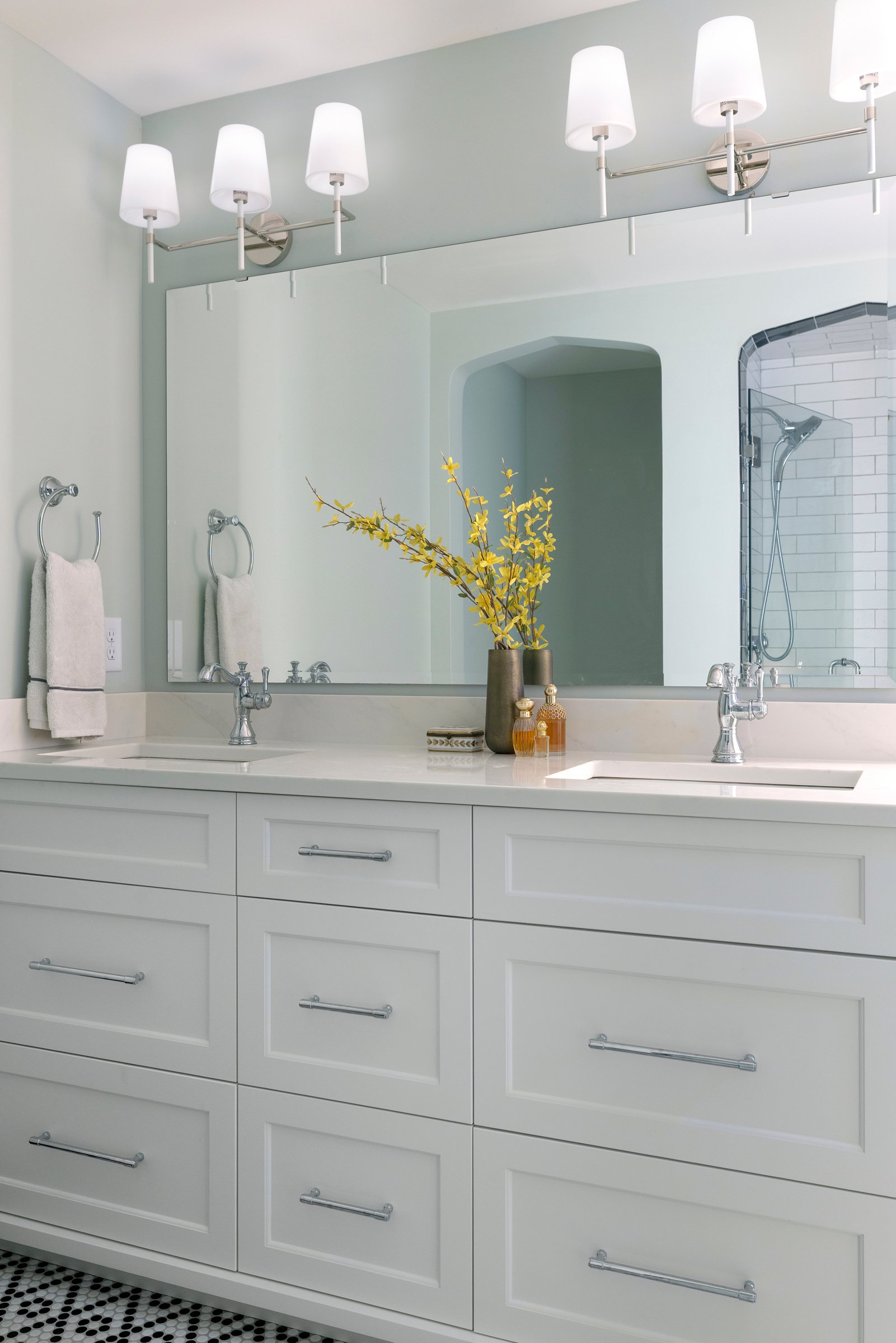 Primary bathroom with double vanity, warm wood tones, and layered lighting