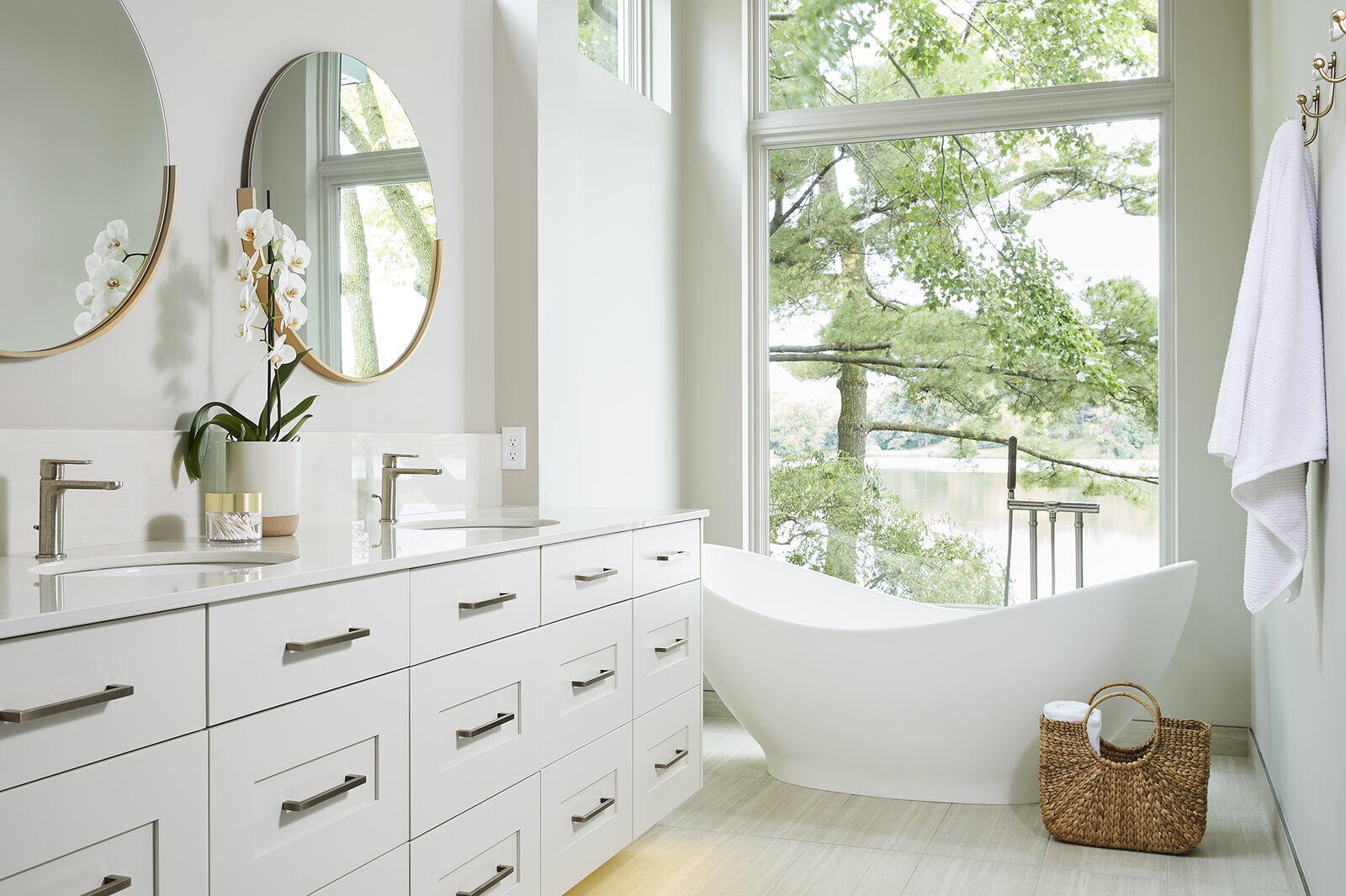 Bright bathroom with double sinks and a freestanding tub in a custom home by MA Peterson, Twin City