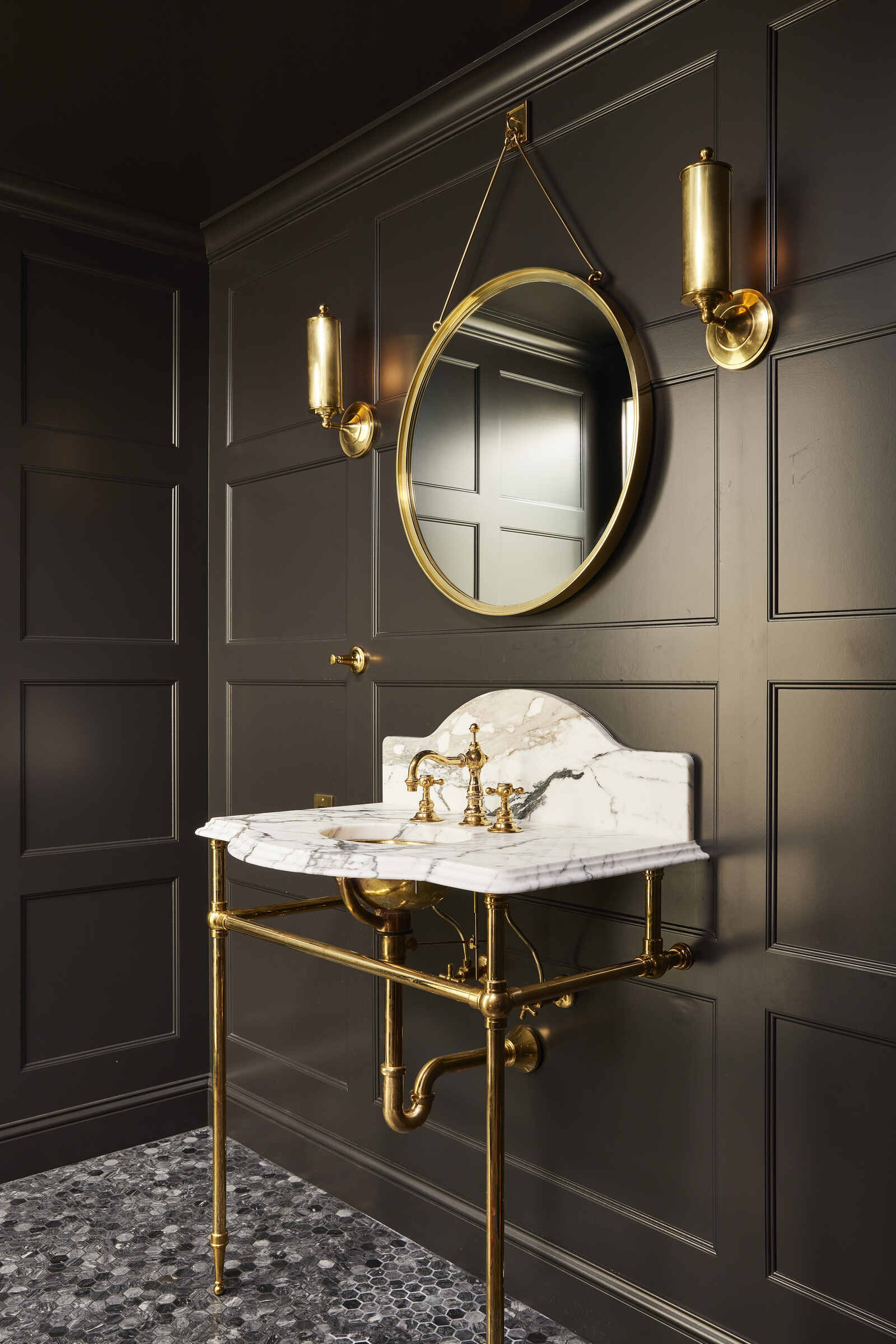 Elegant powder room with black paneled walls and a marble sink in a custom home by MA Peterson, Twin City